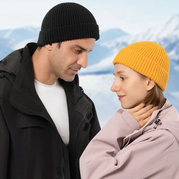 A man and a woman looking at each other outdoors, one wearing a black coat and the other an orange knitted beanie.