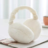 A white plush fur ear warmer or earmuffs resting on a white surface.