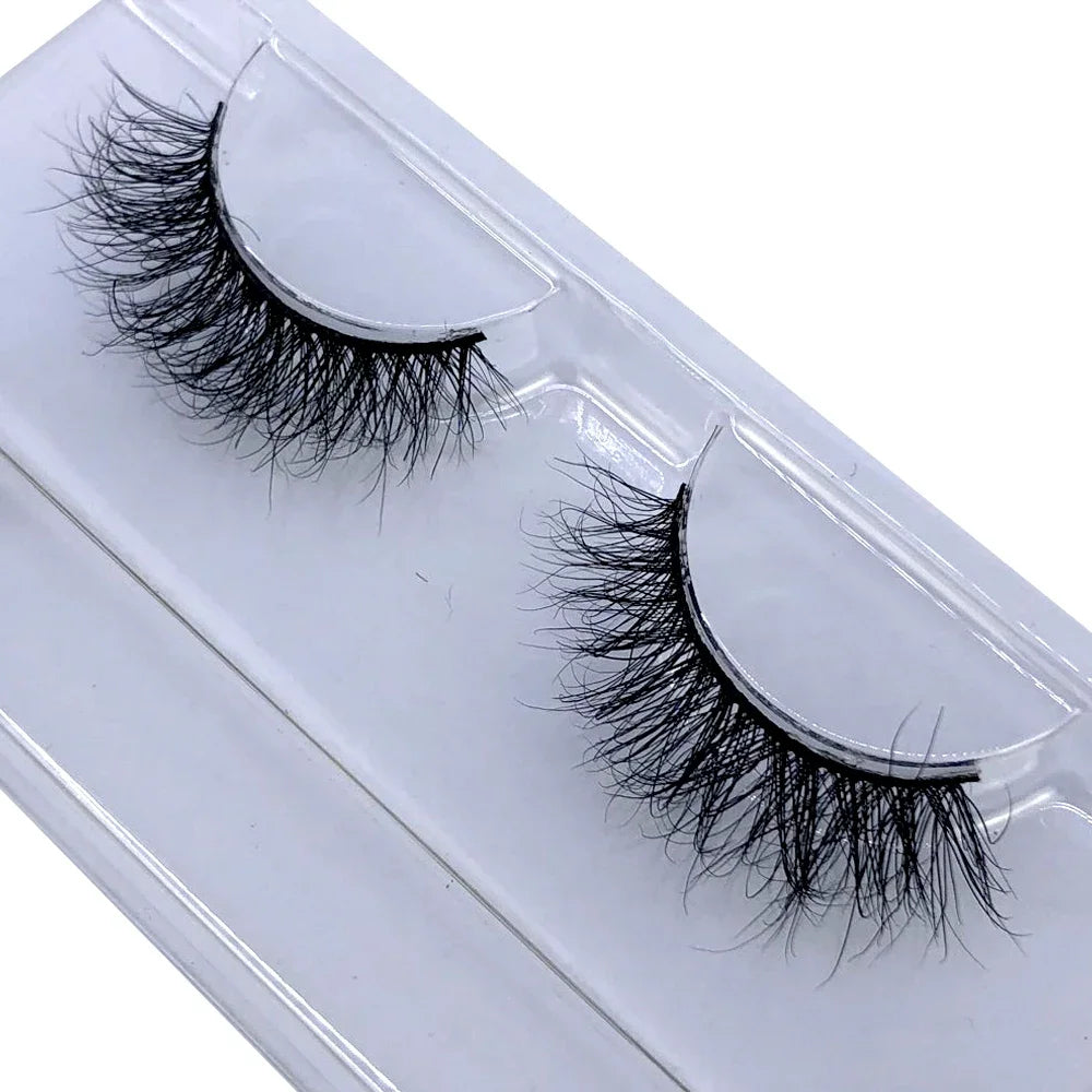 A pair of natural mink false eyelashes displayed in a clear plastic container.