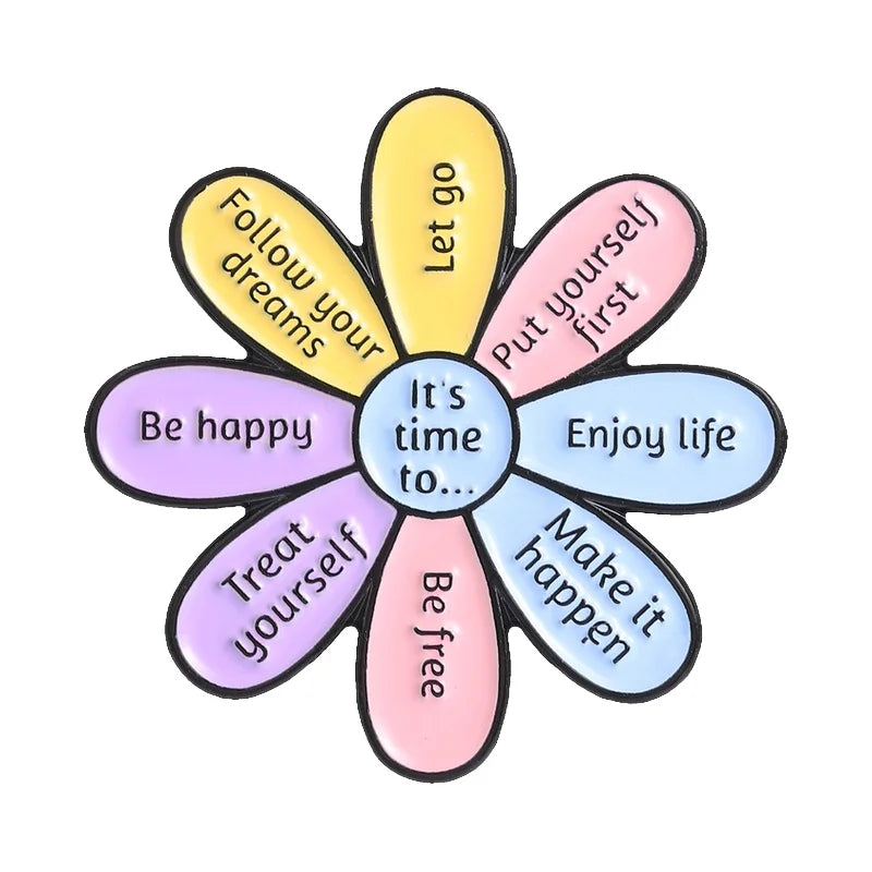 A colorful enamel flower brooch set with petals inscribed with positive affirmations like Follow your dreams and Let go.