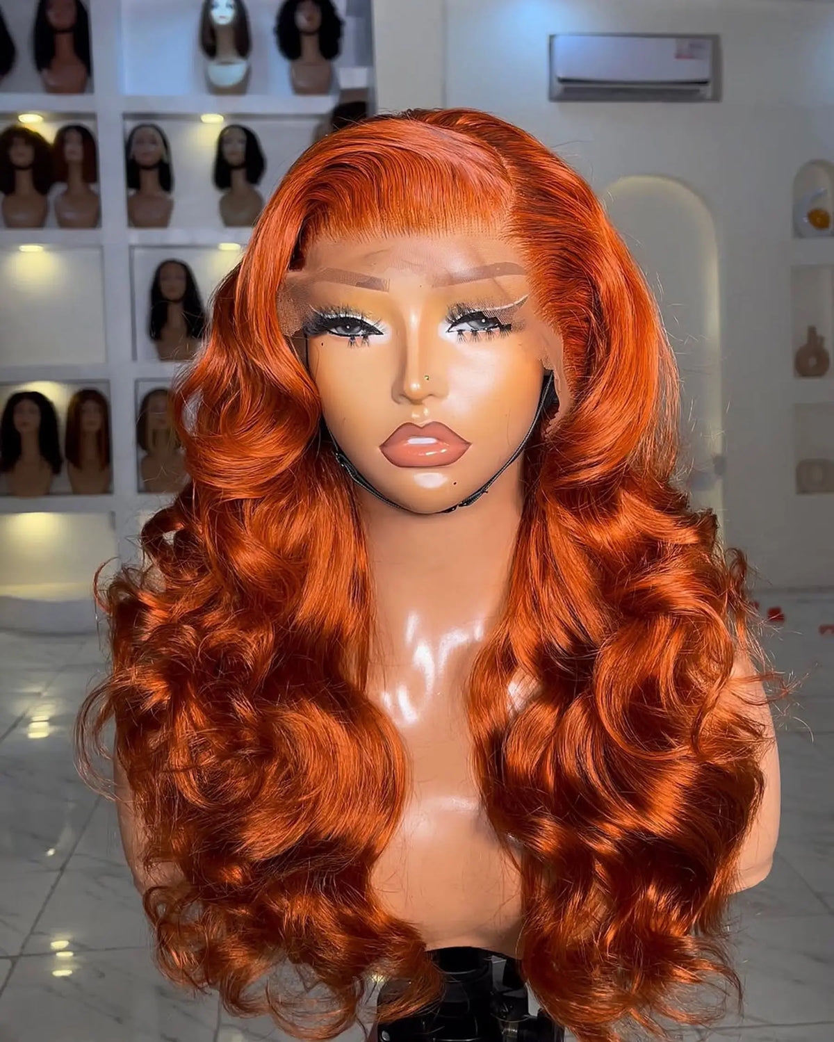 A vibrant orange loose wave wig with a lace front displayed on a mannequin head.