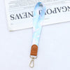 Hellblaue gemusterte Leder-Handy-Lanyard mit goldfarbener Schnalle.