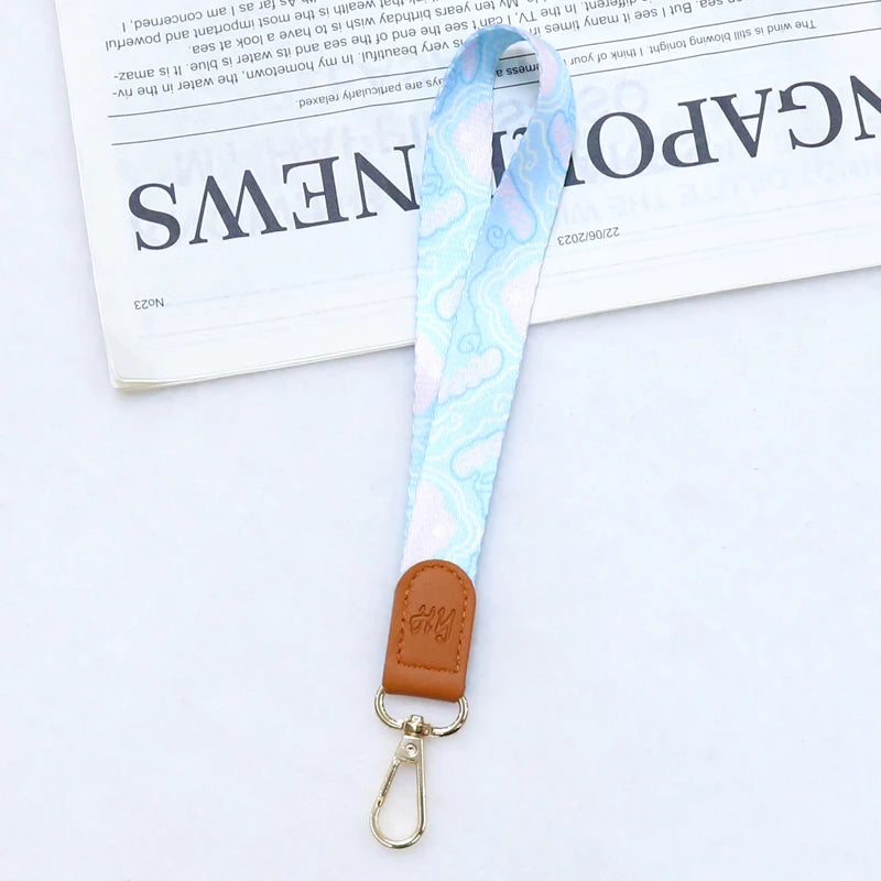 Hellblaue gemusterte Leder-Handy-Lanyard mit goldfarbener Schnalle.