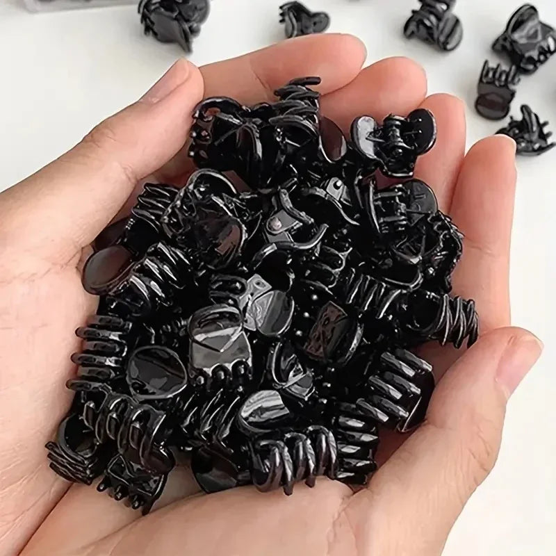 A hand holds a pile of black adjustable hair claw clips.