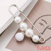 A silver safety pin decorated with multiple white pearls and clear stones, shown on a brown card.