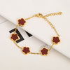 Pulsera de acero inoxidable chapado en oro con pequeños colgantes en forma de flor y esmalte marrón rojizo.