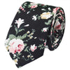 Une cravate noire à motif floral élégant avec des roses roses et crème et du feuillage vert.