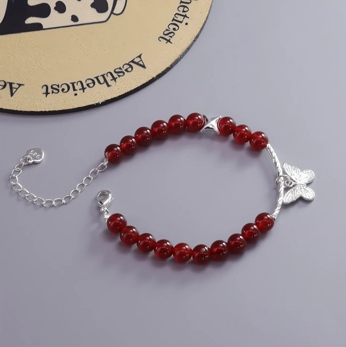 A sterling silver double heart charm bracelet with round red beads displayed on a light background.