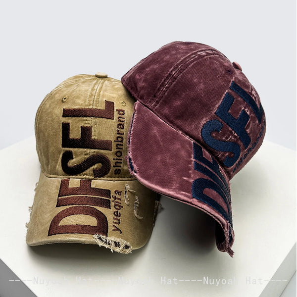 A close-up of a maroon velvet embroidered letter baseball cap with tan fabric and brown lettering.