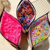 A close-up of several packets of colorful disposable rubber hair ties for kids, showing various bright colors like pink, blue
