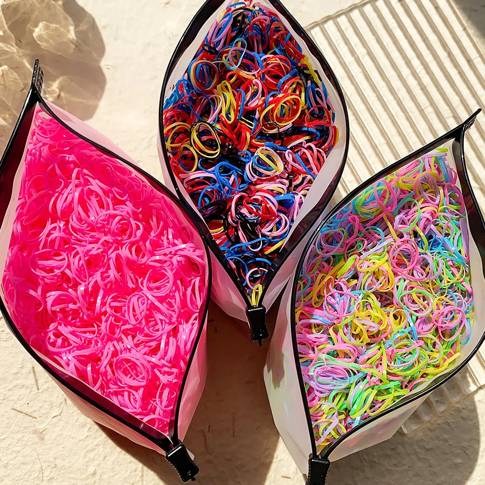 A close-up of several packets of colorful disposable rubber hair ties for kids, showing various bright colors like pink, blue