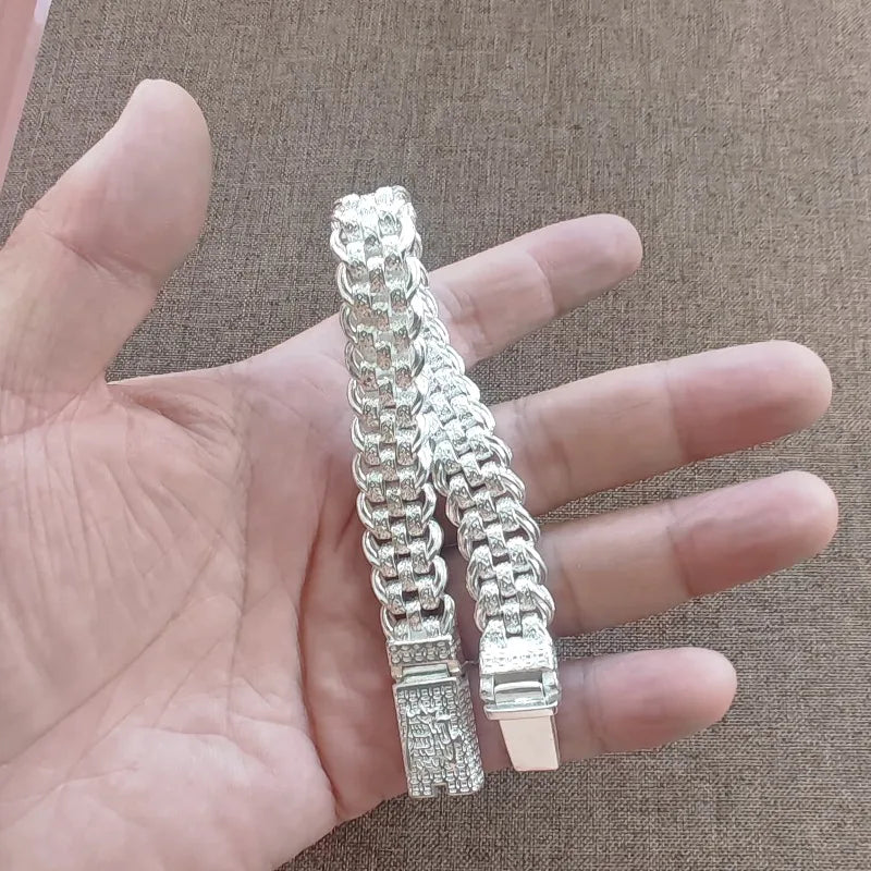 Eine Hand hält ein Vintage-Silber-Schädelarmband für Männer, das die detaillierte Kette und den Anhänger zeigt.