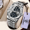 Montre en acier inoxydable argenté avec bracelet en cuir noir et étiquette violette, présentée sur une surface claire.