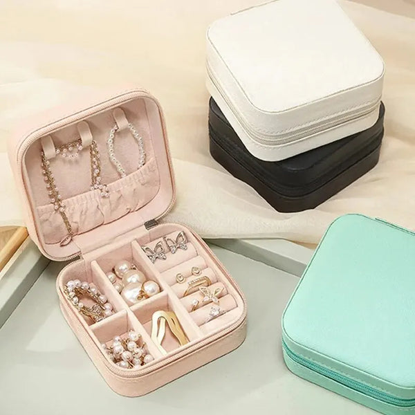 A pink compact leather jewelry travel organizer with multiple compartments and a black storage box.