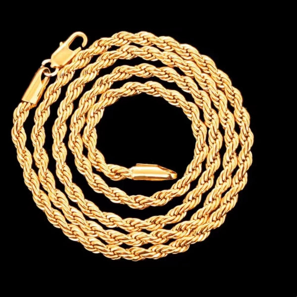 A close-up of a thick, braided 18K gold rope charm necklace coiled on a black background.