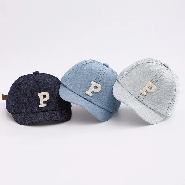 Three baseball caps in navy blue, light blue, and gray with a gold initial P