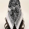 A black and white floral satin shawl tied around a dark hair