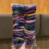 Ein Bündel bunter elastischer Haargummis in verschiedenen Blautönen, Violett und Braun vor einem verschwommenen Holz Hintergr