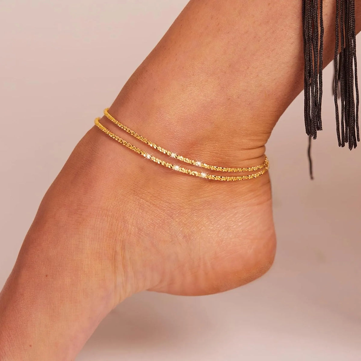Gold silver plated adjustable beaded anklets worn on a person's ankle.