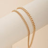 A close-up of a gold plated minimalist Cuban link anklet worn on a person's ankle.