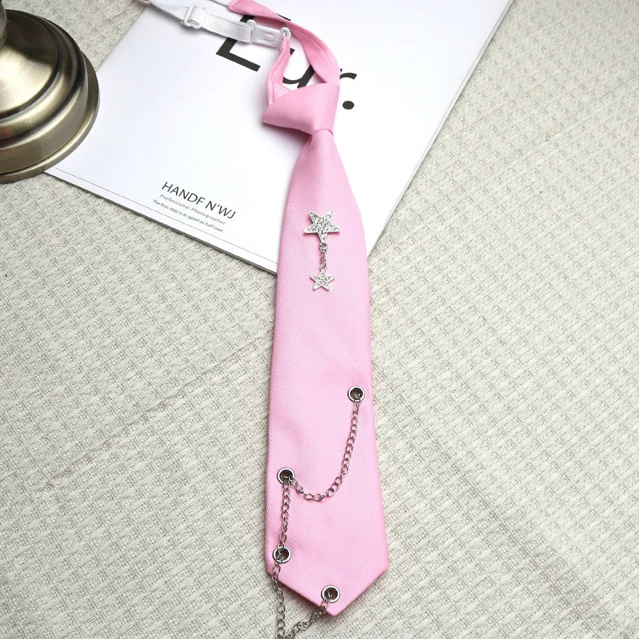 A pink tie with a silver chain star pendant is displayed on a light gray fabric.