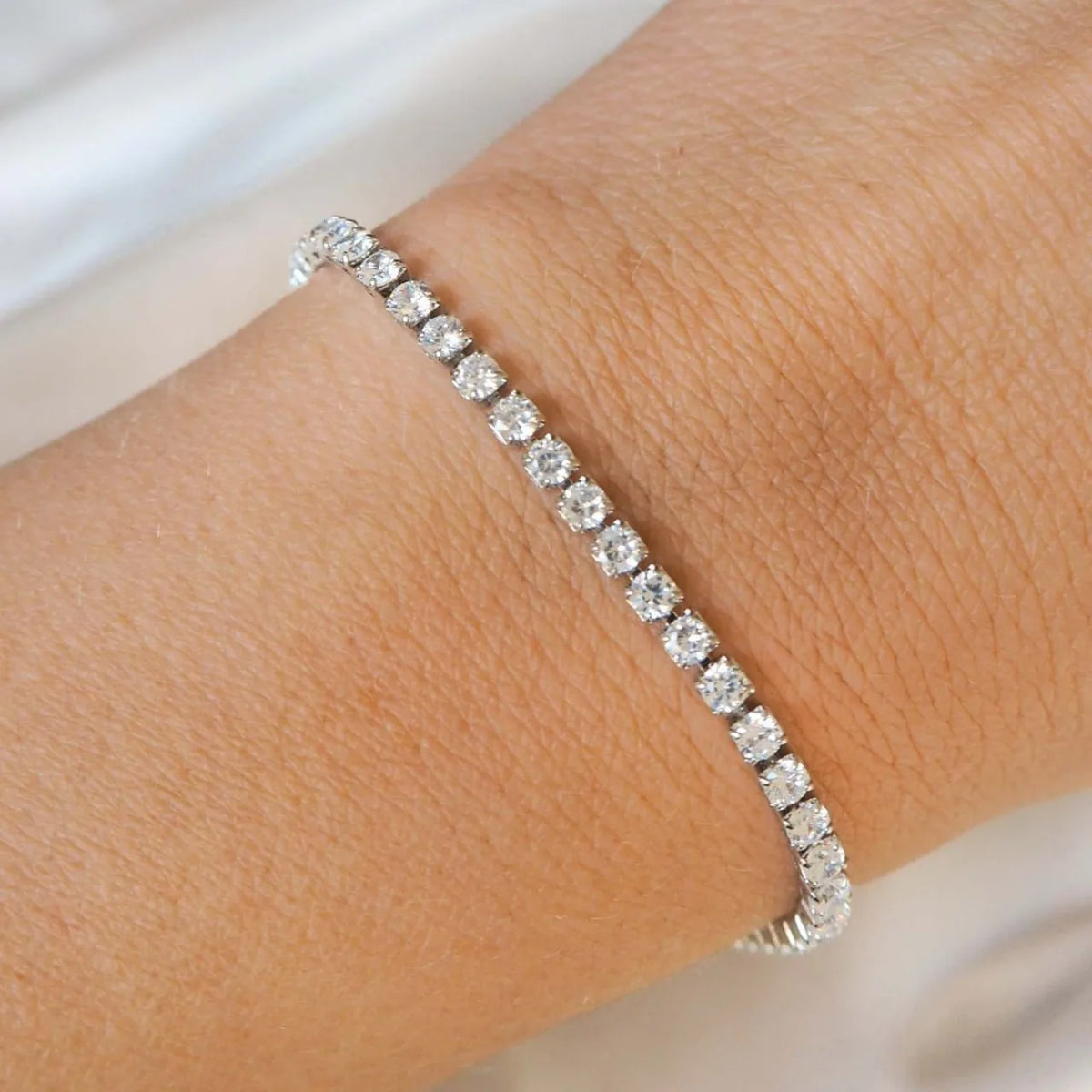 Primer plano de una pulsera de plata incrustada con pequeñas piedras de circonita cúbica transparentes.