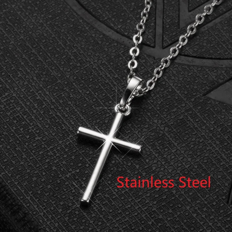 Silberne Edelstahlkreuz-Halskette und Ohrringe-Set auf dunker strukturierter Oberfläche.