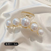 A delicate gold-toned hair claw featuring several round simulated pearls.