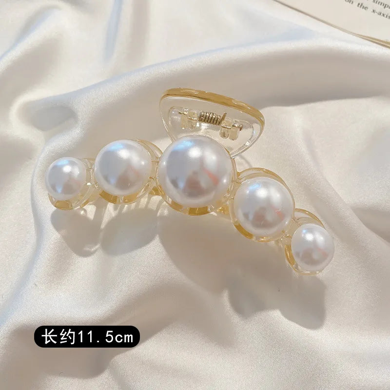 A delicate gold-toned hair claw featuring several round simulated pearls.