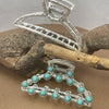 Silver metal hair claw clips decorated with turquoise beads resting on a piece of wood.