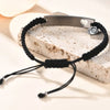 Maßgeschneidertes Edelstahl-Paararmband-Set mit Silberstab und schwarzem Schnur mit Herzanhänger auf hellem Stein