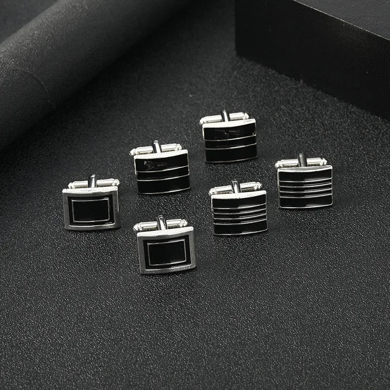 Une collection de boutons de manchette carrés rayés argent et noir, présentés sur une surface sombre.