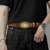 A close-up of a person wearing a brown leather Western belt with a gold printed buckle and a silver watch over a black t-shir
