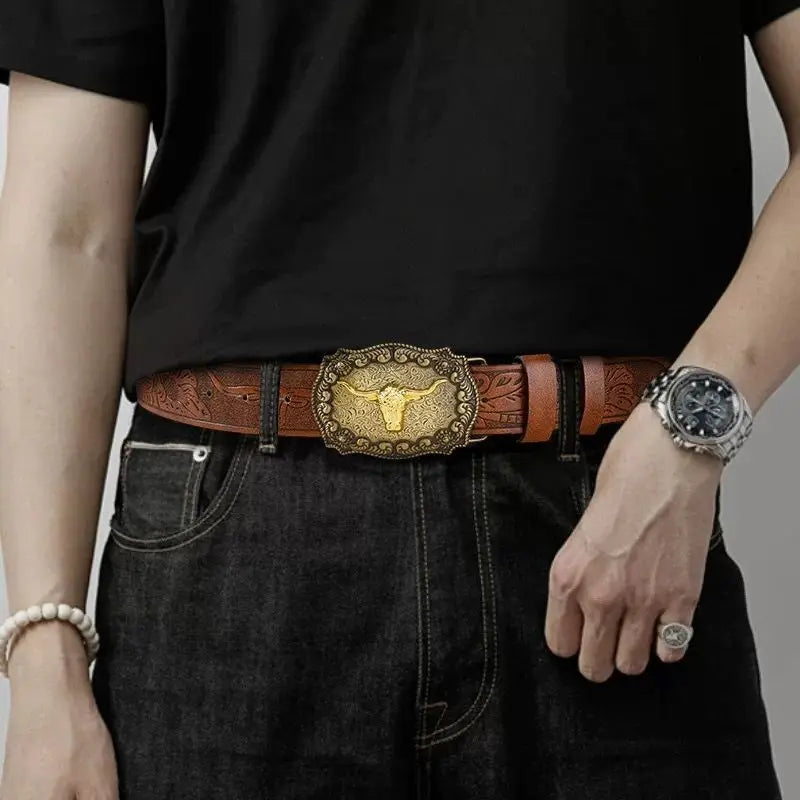 A close-up of a person wearing a brown leather Western belt with a gold printed buckle and a silver watch over a black t-shir