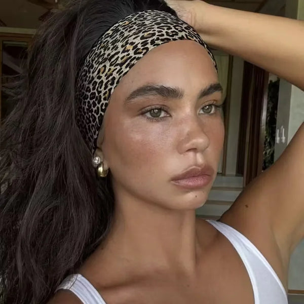 A woman wearing a leopard print waterproof sports headband, looking directly at the camera.