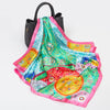 A luxury silk square scarf featuring vibrant pink, green, and blue floral patterns.