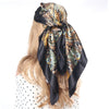 Schwarzer und goldener Boho-Seiderschal, gebunden als Kopftuch um blonde Haare.