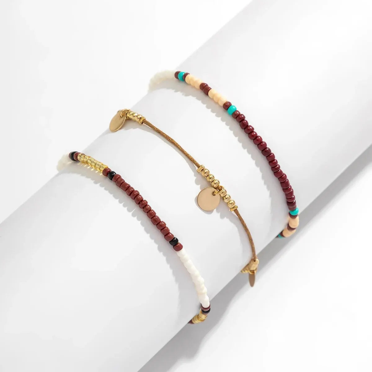 A set of bohemian sequin rice bead anklets featuring various earth tones and natural beads.