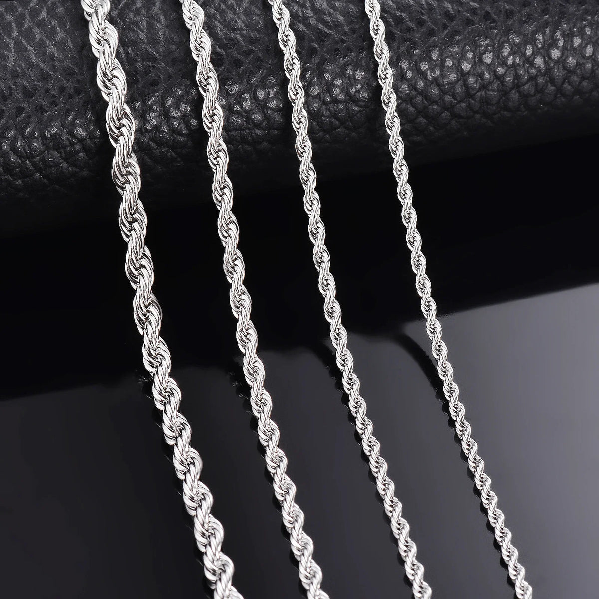 Primer plano de un collar de cadena de cuerda plateada colgado contra un fondo oscuro.