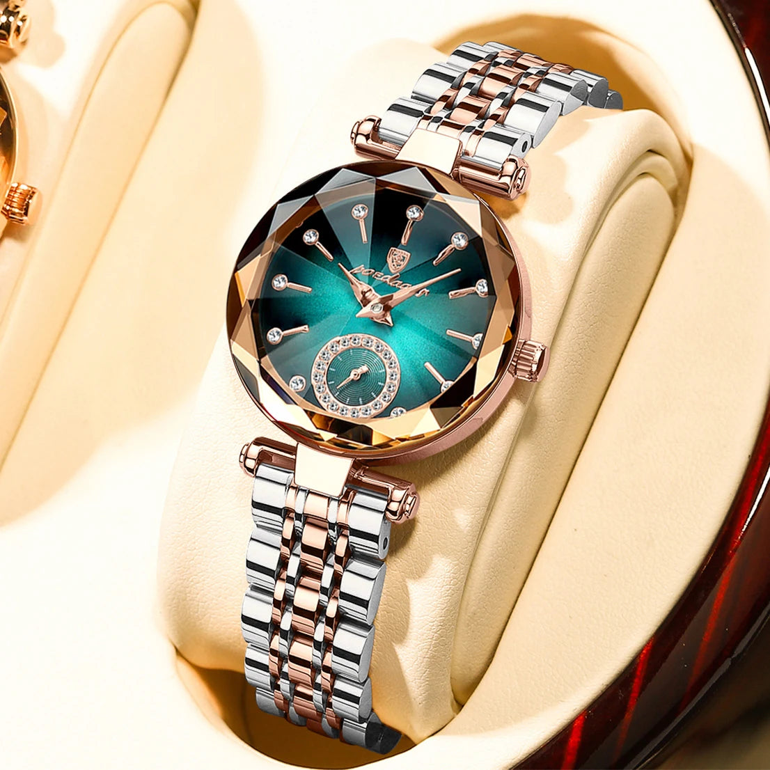 A close-up of an elegant stainless steel quartz ladies wristwatch with a teal dial and rose gold accents, displayed on a ligh