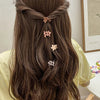 A woman with long brown hair styled in a braid and adorned with a set of colorful mini flower hair clips.