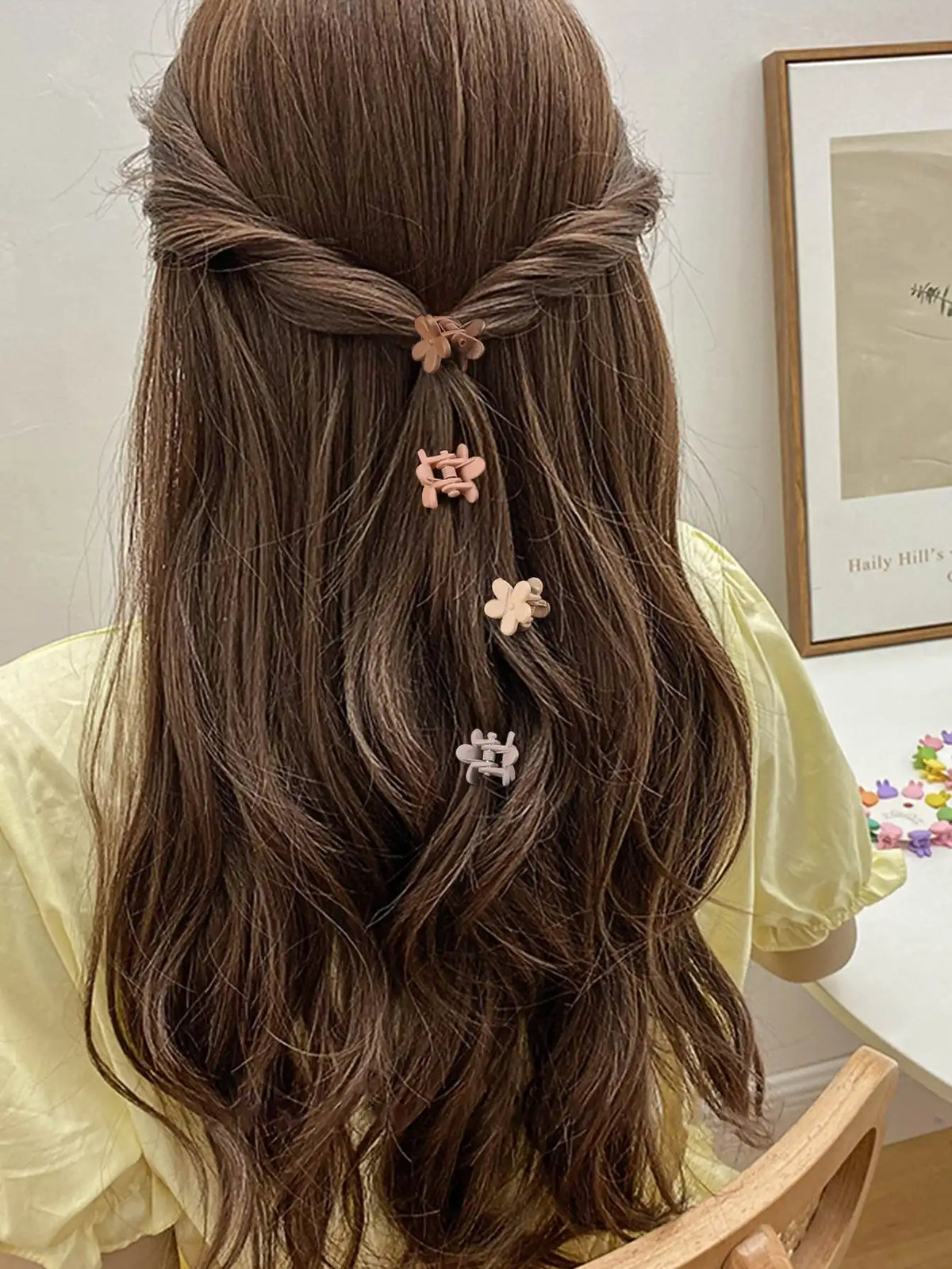A woman with long brown hair styled in a braid and adorned with a set of colorful mini flower hair clips.