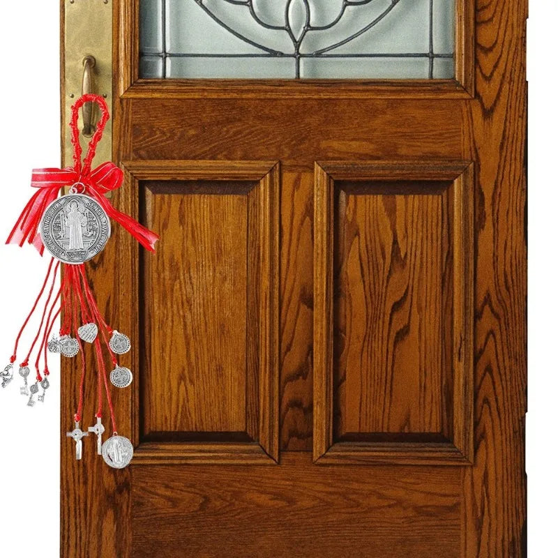 A wooden door featuring a glass panel and a hanging silver Saint Benedict medal protection charm with red ribbon.
