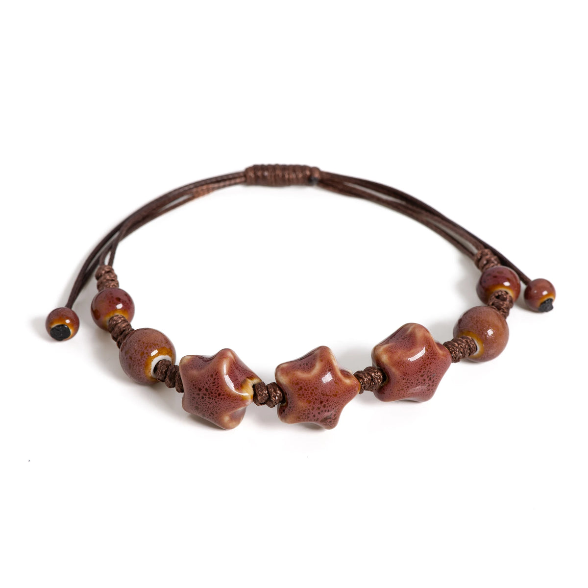 A handmade glazed ceramic star bracelet with dark brown beads and a leather cord.