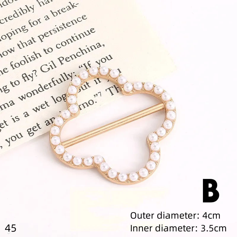Gold-toned decorative button clips shaped like a heart, adorned with small white pearls.