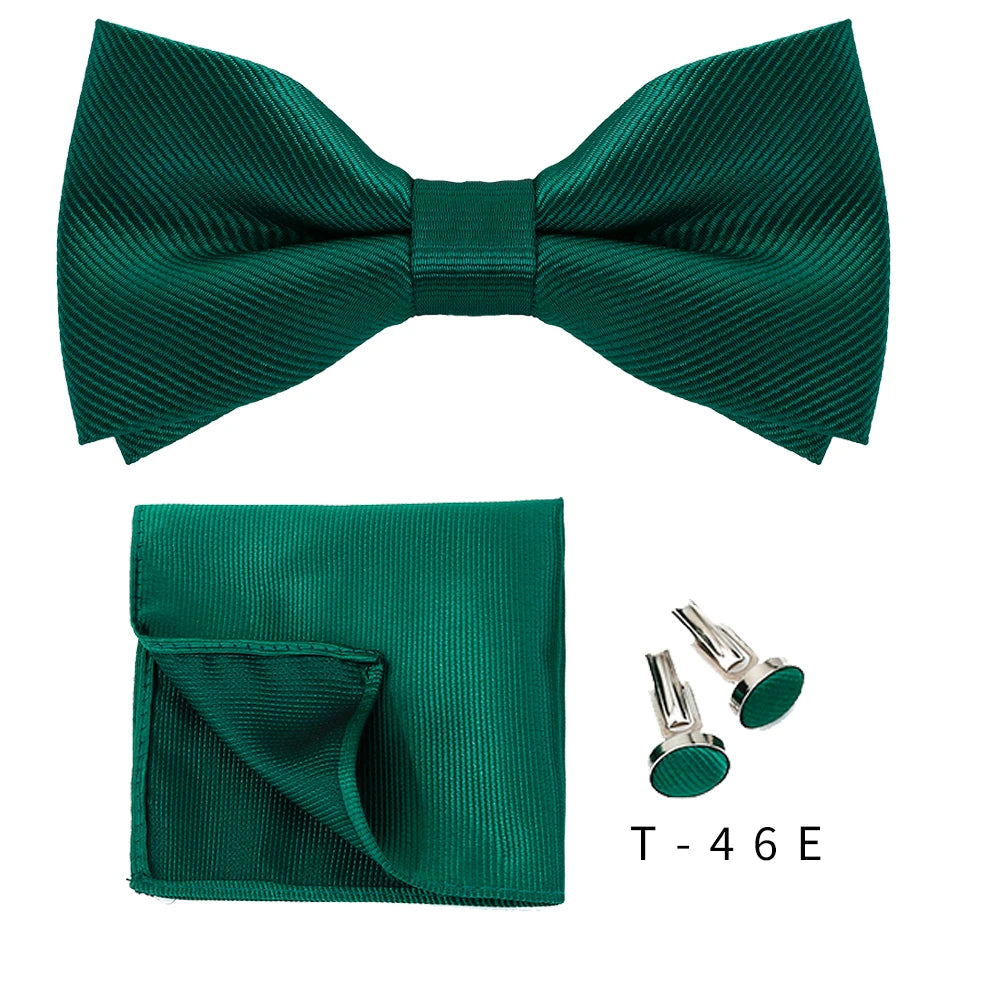 A dark emerald green bow tie and cufflink set displayed against a white background.