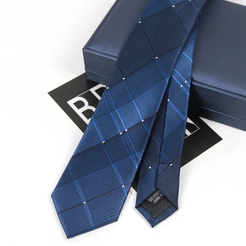A dark blue striped skinny necktie is displayed next to its presentation box.