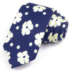 Cravate bleu marine à motif floral blanc et pois, pliée avec soin.