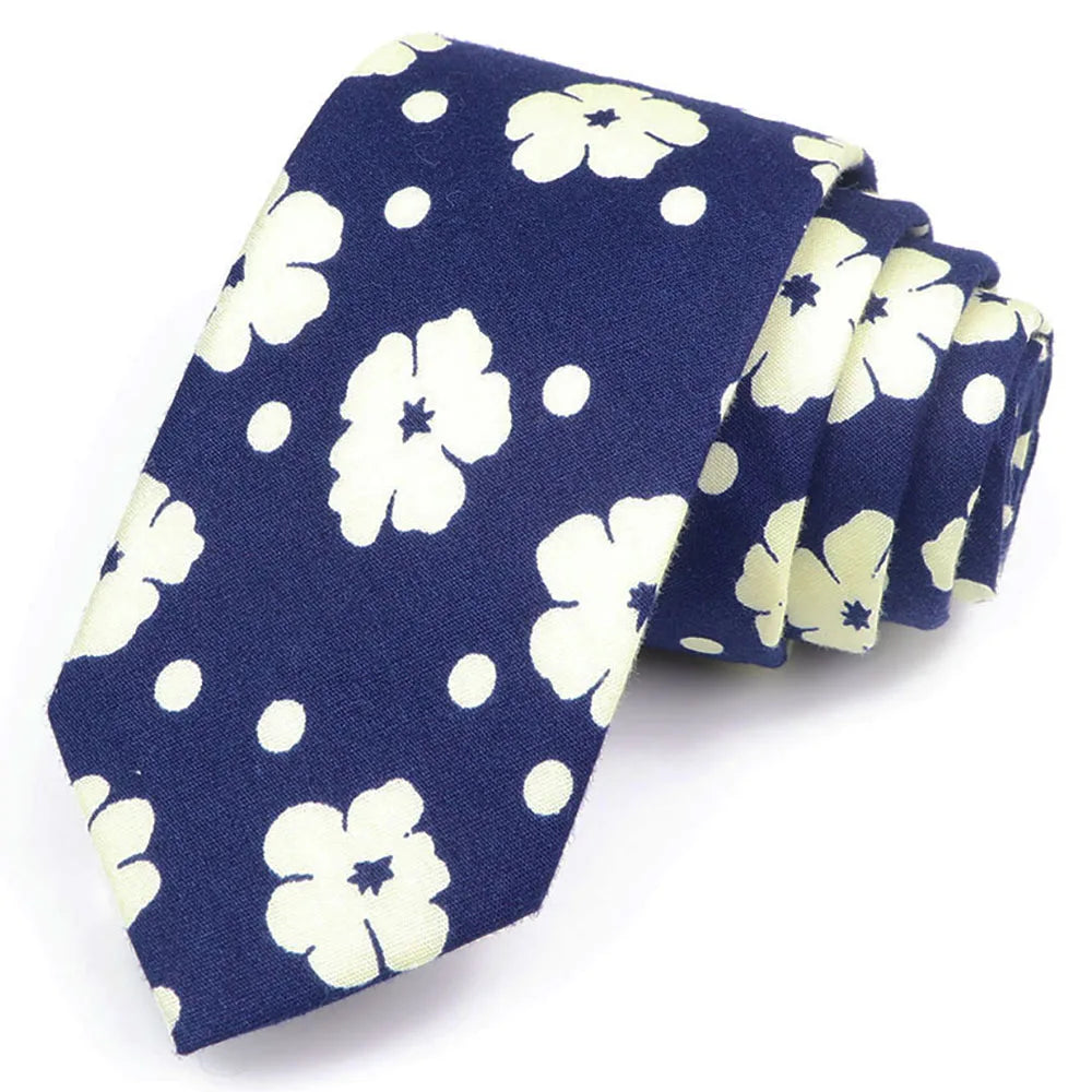 Cravate bleu marine à motif floral blanc et pois, pliée avec soin.