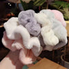 Une pile de élastiques pour cheveux en tricot flou aux couleurs pastel, incluant rose, blanc et lavande.